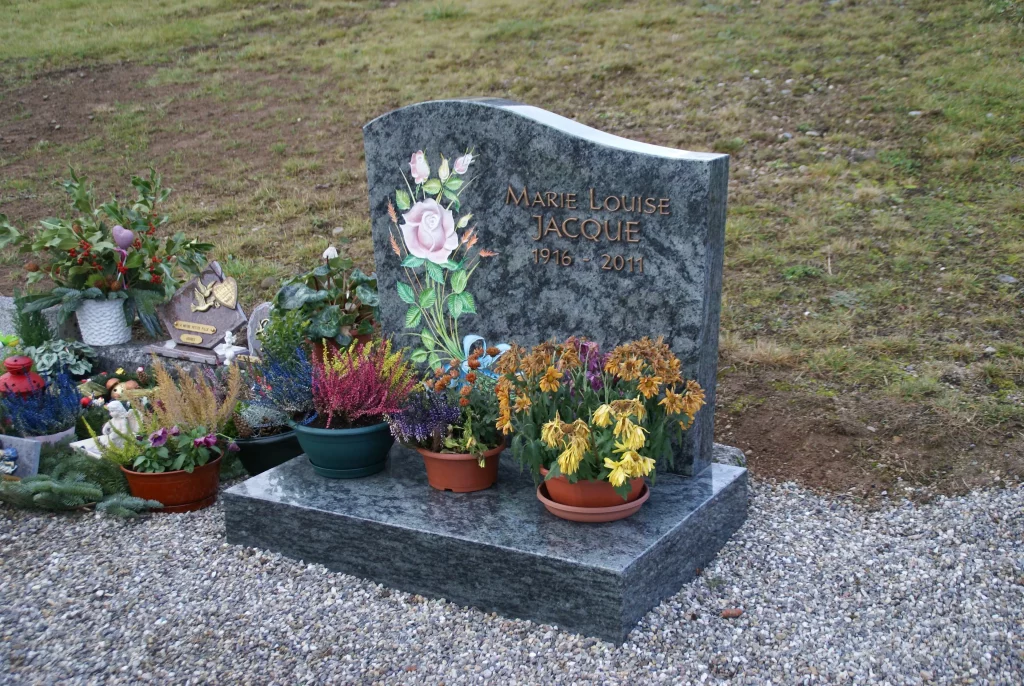 Monument funéraire en granit avec gravure florale personnalisée et fleurs - Marbrerie Claudepierre